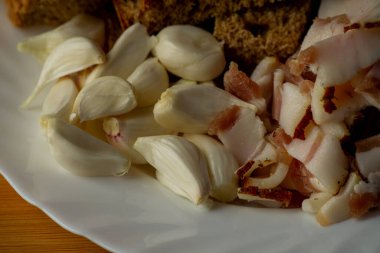 Sarımsak ve pastırma ve sarımsak. Tahtadaki masada pastırma ve sarımsak. Yemek fotoğrafçılığı. Yemek, pastırma, sarımsak ve siyah çavdar ekmeği..