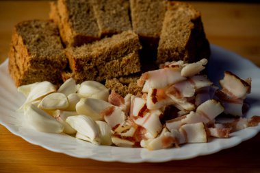 Sarımsak ve pastırma ve sarımsak. Tahtadaki masada pastırma ve sarımsak. Yemek fotoğrafçılığı. Yemek, pastırma, sarımsak ve siyah çavdar ekmeği..