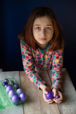 Mutlu Paskalyalar. Kız ve mor renkli yumurtalar. Paskalya gelenekleri. Ergen, kız 9 yaşında. Şarlatan bir kız. Puantiyeli elbise giymiş bir çocuk. Tatiller, ilkbahar