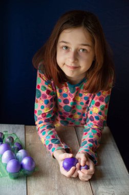 Mutlu Paskalyalar. Kız ve mor renkli yumurtalar. Paskalya gelenekleri. Ergen, kız 9 yaşında. Şarlatan bir kız. Puantiyeli elbise giymiş bir çocuk. Tatiller, ilkbahar