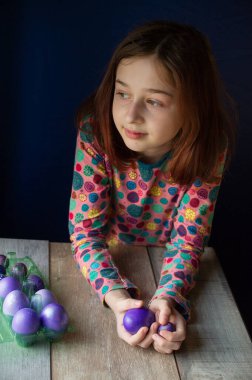 Mutlu Paskalyalar. Kız ve mor renkli yumurtalar. Paskalya gelenekleri. Ergen, kız 9 yaşında. Şarlatan bir kız. Puantiyeli elbise giymiş bir çocuk. Tatiller, ilkbahar