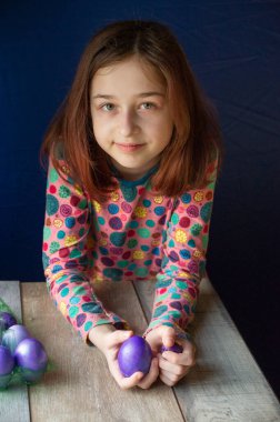 Mutlu Paskalyalar. Kız ve mor renkli yumurtalar. Paskalya gelenekleri. Ergen, kız 9 yaşında. Şarlatan bir kız. Puantiyeli elbise giymiş bir çocuk. Tatiller, ilkbahar