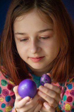 Mutlu Paskalyalar. Kız ve mor renkli yumurtalar. Paskalya gelenekleri. Ergen, kız 9 yaşında. Şarlatan bir kız. Puantiyeli elbise giymiş bir çocuk. Tatiller, ilkbahar