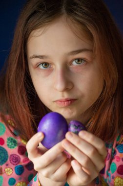 Mutlu Paskalyalar. Kız ve mor renkli yumurtalar. Paskalya gelenekleri. Ergen, kız 9 yaşında. Şarlatan bir kız. Puantiyeli elbise giymiş bir çocuk. Tatiller, ilkbahar