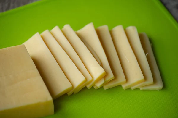 切碎的奶酪在木板上 顶部视图 在绿色的板子上切碎硬奶酪 — 图库照片