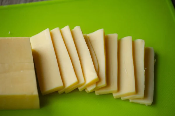 切碎的奶酪在木板上 顶部视图 在绿色的板子上切碎硬奶酪 — 图库照片