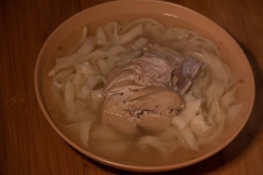 Tavuk Erişte Çorbası. Turuncu bir tabakta portakal masa örtüsü üzerinde tavuk ve şehriye çorbası. Yemek fotoğrafçılığı. Sıcak yemek. Erişteli çorba. Tavuk, erişte. Ev yapımı erişte ve çorba.