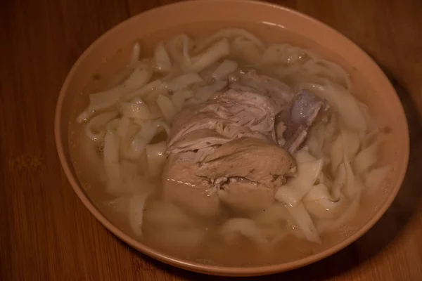 Chicken Noodle Soup. Chicken and noodle soup on an orange tablecloth in an orange plate. Food photography. Hot dish. Broth with noodles. Chicken, noodles. Homemade noodles and broth