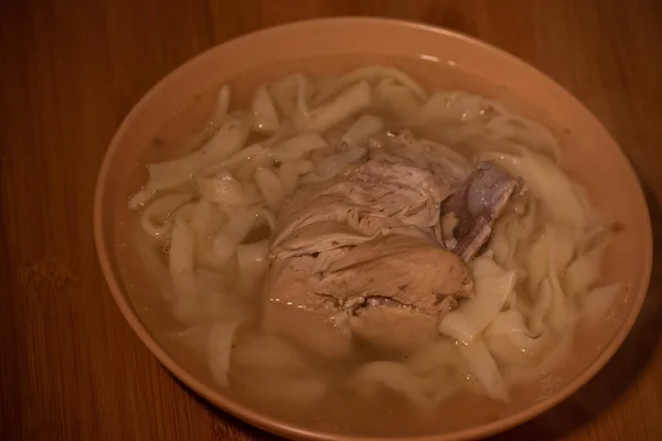 Chicken Noodle Soup. Chicken and noodle soup on an orange tablecloth in an orange plate. Food photography. Hot dish. Broth with noodles. Chicken, noodles. Homemade noodles and broth