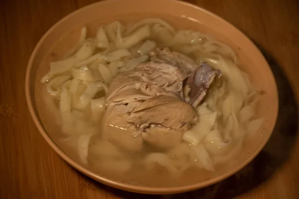 Chicken Noodle Soup. Chicken and noodle soup on an orange tablecloth in an orange plate. Food photography. Hot dish. Broth with noodles. Chicken, noodles. Homemade noodles and broth