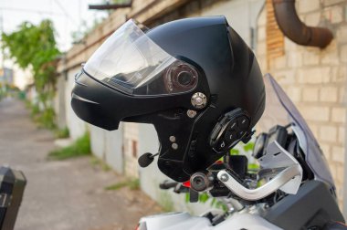 Motosikletlinin kaskı bir motosikletin sapında asılı. Motosikletin direksiyonunda asılı duran miğfer. Motorcu ve motosiklet konsepti.