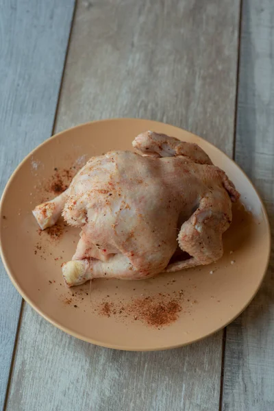 木製のテーブルの上に生の鶏全体 生チキン 台所で家庭で鶏を調理する — ストック写真