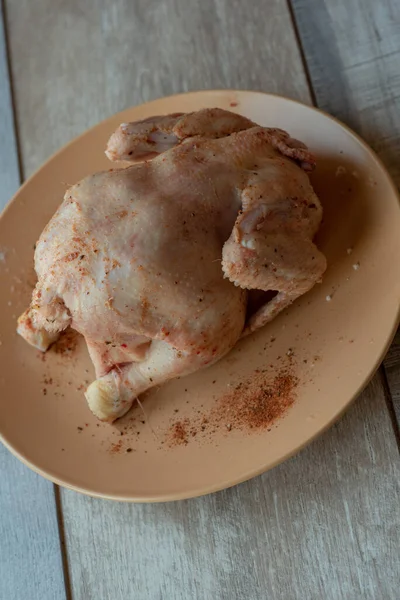 木製のテーブルの上に生の鶏全体 生チキン 台所で家庭で鶏を調理する — ストック写真