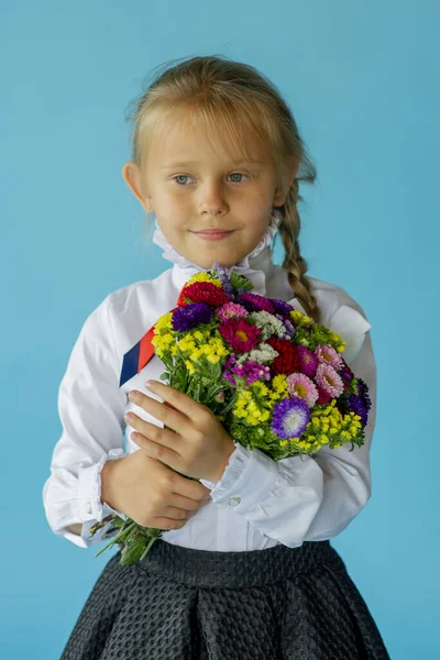 青いスタジオの背景に隔離された白いTシャツの6歳の少女は かなりヨーロッパの外観の子は カメラで室内の笑みを浮かべて見てポーズ 世代Zの概念 女の子女子高生オン青の背景 — ストック写真