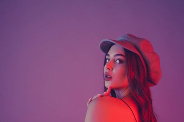 Göz kamaştırıcı genç kadın dalgalı saçlarıyla şık bir elbise giyer. Siyah elbiseli ve gri şapkalı bir kız. Kahverengi kıvırcık saçlı kız. Portre. Pembe arka planda güzel, şık bir kadın.