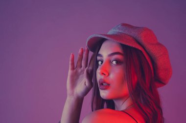 Göz kamaştırıcı genç kadın dalgalı saçlarıyla şık bir elbise giyer. Siyah elbiseli ve gri şapkalı bir kız. Kahverengi kıvırcık saçlı kız. Portre. Pembe arka planda güzel, şık bir kadın.