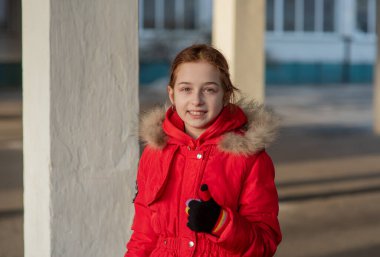 Dokuz yaşında güzel bir kızın portresi. Kış kıyafetleri içinde okul çocuğu. Kız 9 yaşında. Genç, portre. Kırmızı ceketli kız. Yeni nesil. Z neslinin çocukları.