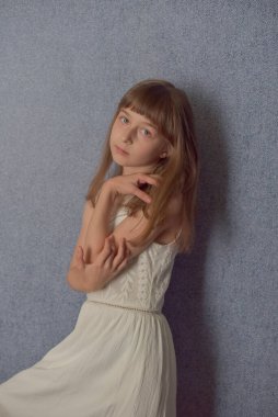 Portre. 9 yaşında bir kız, mavi duvar kağıdının arkasında. Çocuk virüs sırasında evde kalıyor. Liseli kız evde kaldı. Okul çağında beyaz dantel elbiseli küçük bir kız. Z nesli çocuklar