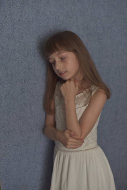 Portre. 9 yaşında bir kız, mavi duvar kağıdının arkasında. Çocuk virüs sırasında evde kalıyor. Liseli kız evde kaldı. Okul çağında beyaz dantel elbiseli küçük bir kız. Z nesli çocuklar