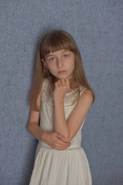 肖像画 青の壁紙を背景に少女9歳 子供はウイルスの間家に残る 女子高生は家にいる 白いレースのドレスを着た女子高生 Z世代の子供 — ストック写真