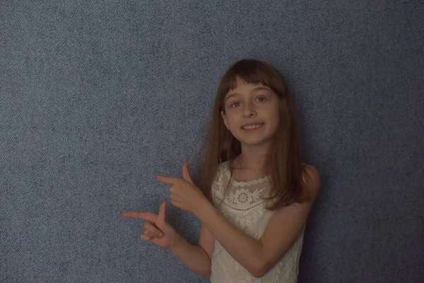女孩9岁背景蓝色墙纸 这个孩子在病毒传播期间一直呆在家里 女学生在家里 穿着白花边衣服的学龄小女孩 Z代儿童 — 图库照片