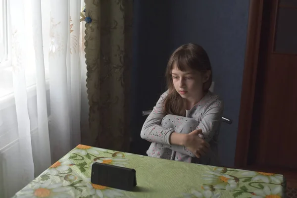 Schoolgirl home schooling. A schoolgirl stays home to study. Portrait of a girl of 9 years old. The child sit next to the window at the table. Children of the Z-generation. Portrait of a little girl.