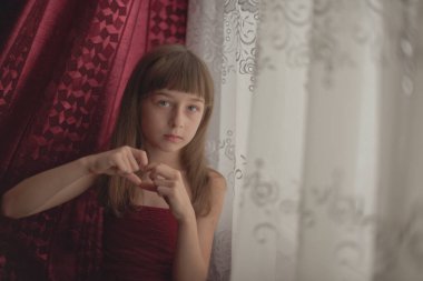 Liseli kız evde. Liseli bir kız evde kalır. 9 yaşında bir kızın portresi. Çocuk pencerenin yanına oturdu. Z jenerasyonunun çocukları. Küçük bir kızın portresi. Genç, koronavirüs, covid-19