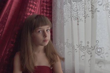 Liseli kız evde. Liseli bir kız evde kalır. 9 yaşında bir kızın portresi. Çocuk pencerenin yanına oturdu. Z jenerasyonunun çocukları. Küçük bir kızın portresi. Genç, koronavirüs, covid-19