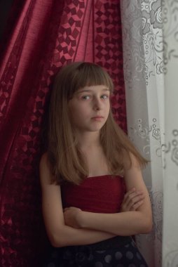 Liseli kız evde. Liseli bir kız evde kalır. 9 yaşında bir kızın portresi. Çocuk pencerenin yanına oturdu. Z jenerasyonunun çocukları. Küçük bir kızın portresi. Genç, koronavirüs, covid-19