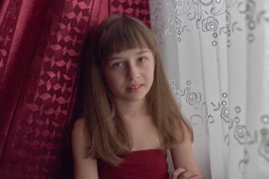 Liseli kız evde. Liseli bir kız evde kalır. 9 yaşında bir kızın portresi. Çocuk pencerenin yanına oturdu. Z jenerasyonunun çocukları. Küçük bir kızın portresi. Genç, koronavirüs, covid-19