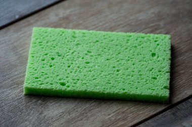 Selüloz sünger mutfak objeleri ahşap doku arka planında. Selüloz peçete masanın üstünde..