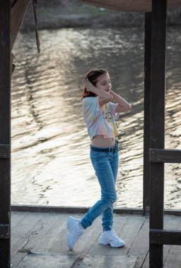 Güzel genç bir kadının portresi. Nehir kenarında plein hava çekimi. Bir gencin portresi. Kız 9 yaşında. Öğrenci kızlar nehrin yanında yürürler. Nehir. Bahar günbatımında kız