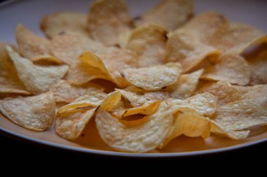 Patates cipsli bir kaseye yakın çekim. Tabakta patates cipsi. Yemek fotoğrafçılığı. Cips makro fotoğraf. Patates yemeği, atıştırmalık.,