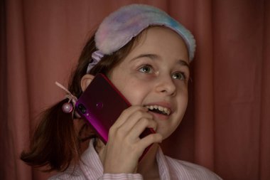 İnsanlar ve eğlence konsepti. Kırmızı ceketli bir kız selfie çekiyor. Evinde elinde telefon olan 9 yaşında bir kız. Pijamalı bir genç. Ev elbiseli küçük kız..