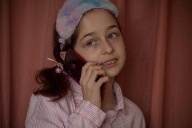 İnsanlar ve eğlence konsepti. Kırmızı ceketli bir kız selfie çekiyor. Evinde elinde telefon olan 9 yaşında bir kız. Pijamalı bir genç. Ev elbiseli küçük kız..