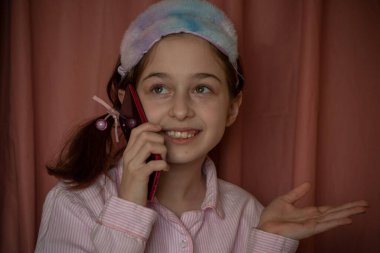 İnsanlar ve eğlence konsepti. Kırmızı ceketli bir kız selfie çekiyor. Evinde elinde telefon olan 9 yaşında bir kız. Pijamalı bir genç. Ev elbiseli küçük kız..