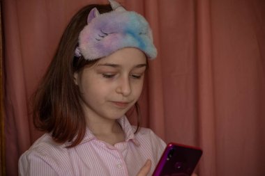 İnsanlar ve eğlence konsepti. Kırmızı ceketli bir kız selfie çekiyor. Evinde elinde telefon olan 9 yaşında bir kız. Pijamalı bir genç. Ev elbiseli küçük kız..