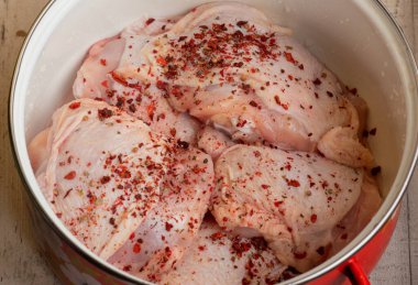 Taze derisi olmayan tavuk butları. Çiğ tavuk budu. Çiğ tavuk budu. Baharatlı tavuk eti tavada kırmızı biber..