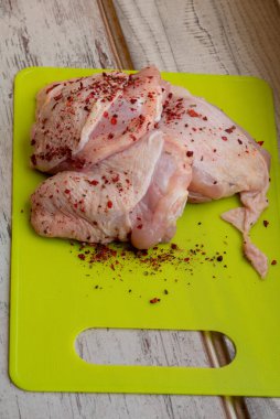 Taze derisi olmayan tavuk butları. Çiğ tavuk budu. Çiğ tavuk budu. Baharatlı tavuk eti tavada kırmızı biber..