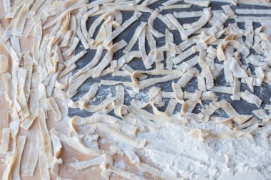 Çiğ sarı İtalyan makarnası. Ev yapımı erişte pişirme işlemi. Ev yapımı erişte. Un, su ve yumurtalı hamur. Pişirme un ürünleri.