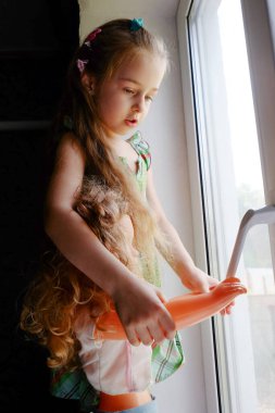 Pencerenin yanındaki küçük kız. Evde pencerenin yanında oturan 5 yaşında bir kız çocuğu. Çocukluk, çocuk, pencere. Evde kal.