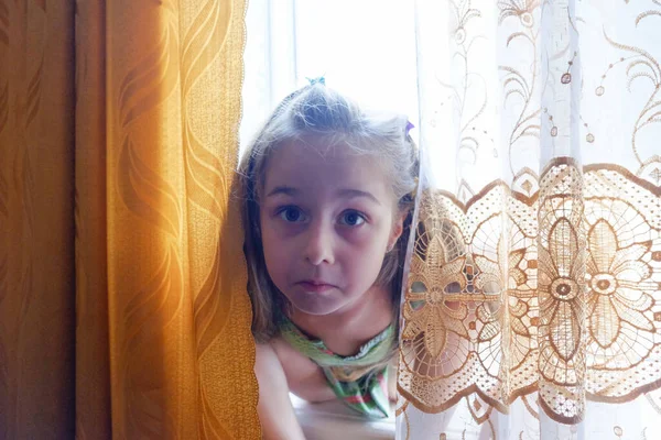 窓のそばの女の子 5歳の少女が家の窓のそばに腰を下ろしている 家にいて — ストック写真