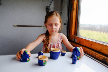 Trendeki tatlı kız. Yaz Tatili ve Seyahat Konsepti. 5-6 yaşlarında bir kız trene biniyor. Gençler seyahat eder. Uzun saçlı küçük kız. Çocuk portresi