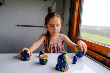 Trendeki tatlı kız. Yaz Tatili ve Seyahat Konsepti. 5-6 yaşlarında bir kız trene biniyor. Gençler seyahat eder. Uzun saçlı küçük kız. Çocuk portresi