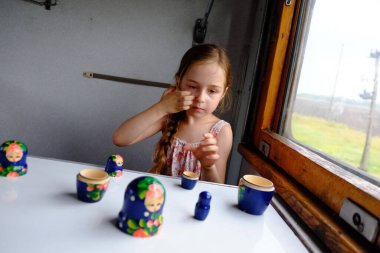 Trendeki tatlı kız. Yaz Tatili ve Seyahat Konsepti. 5-6 yaşlarında bir kız trene biniyor. Gençler seyahat eder. Uzun saçlı küçük kız. Çocuk portresi