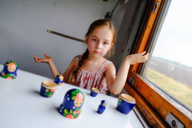 Trendeki tatlı kız. Yaz Tatili ve Seyahat Konsepti. 5-6 yaşlarında bir kız trene biniyor. Gençler seyahat eder. Uzun saçlı küçük kız. Çocuk portresi