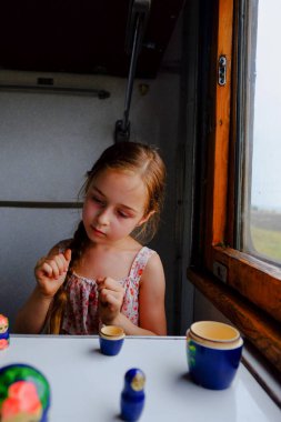 Trendeki tatlı kız. Yaz Tatili ve Seyahat Konsepti. 5-6 yaşlarında bir kız trene biniyor. Gençler seyahat eder. Uzun saçlı küçük kız. Çocuk portresi