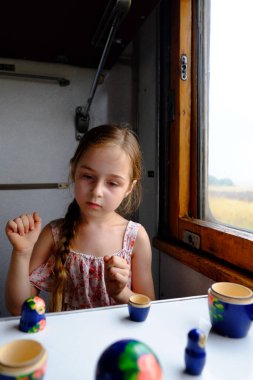 Trendeki tatlı kız. Yaz Tatili ve Seyahat Konsepti. 5-6 yaşlarında bir kız trene biniyor. Gençler seyahat eder. Uzun saçlı küçük kız. Çocuk portresi