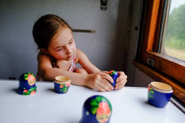 Trendeki tatlı kız. Yaz Tatili ve Seyahat Konsepti. 5-6 yaşlarında bir kız trene biniyor. Gençler seyahat eder. Uzun saçlı küçük kız. Çocuk portresi