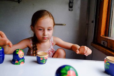 Trendeki tatlı kız. Yaz Tatili ve Seyahat Konsepti. 5-6 yaşlarında bir kız trene biniyor. Gençler seyahat eder. Uzun saçlı küçük kız. Çocuk portresi